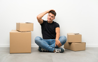Handsome young man moving in new home among boxes laughing