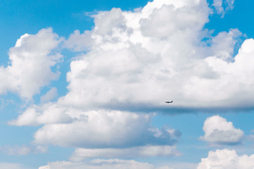 Small passenger plane against a huge clouds in the blue sky