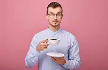 A cheerful responsive student in a light shirt with glasses and a black rim is resting with a white...