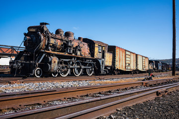 Naklejka premium Vintage train cars and locomotives, covered in rust and are in disrepair, rest on tracks in Scranton, PA, USA.