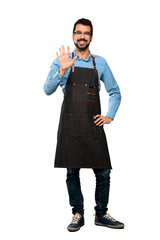 Fototapeta premium Full-length shot of Man with apron counting five with fingers over isolated white background