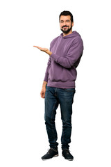 Full-length shot of Handsome man with sweatshirt presenting an idea while looking smiling towards over isolated white background