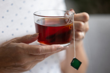 Middle aged woman holding cup of bag tea, closeup view