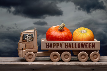 Happy Halloween, orange pumpkins and dry maple leaves in wooden toy truck with  human skeleton....
