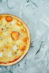 Large oven-baked 4 cheese pizza with mozzarella and blue cheese with mold on a wooden board on a gray background. Italian Cuisine