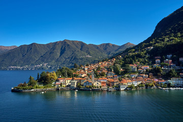 Fototapeta na wymiar Panoramic top view of Lake Como. Lombardy, Italy. The small town of Torno. Autumn season. Perfect clear blue sky. Boats parked off the coast