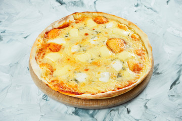 Large oven-baked 4 cheese pizza with mozzarella and blue cheese with mold on a wooden board on a gray background. Italian Cuisine