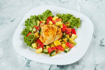 Portion of fresh and healthy salad with warm baked chicken on a gray background. Balanced food.