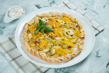 Homemade Hot fruit cake with orange, apples, pears and banana with cream on a gray background. Food at Dessert