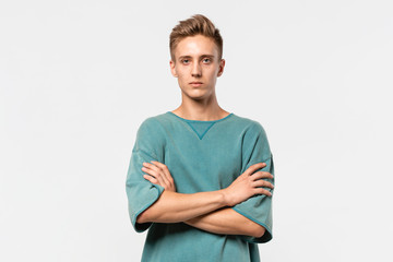 Obraz premium Confedent young man in a green tee holds hands folded isolated over grey background.