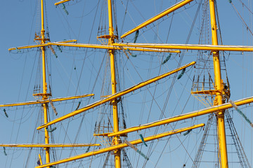 Rays, masts, cables and rigging of a sailing ship close-up.