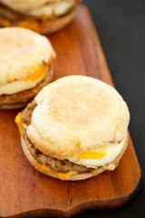 Tasty homemade pork roll egg sandwich on a rustic wooden board on a black background, side view. Closeup.