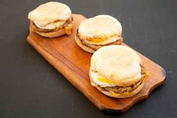 Homemade pork roll egg sandwich on a rustic wooden board on a black background, low angle view. Close-up.