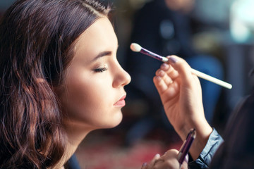 Makeup artist applies natural makeup to the face of the model. Wizard workflow close-up