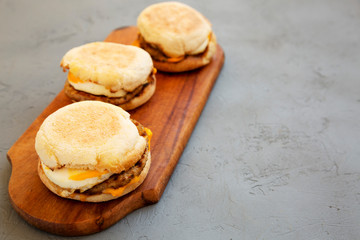 Homemade pork roll egg sandwich on a rustic wooden board on a gray surface, low angle view. Copy space.