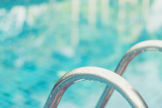 Outdoor swimming pool in hotel with stair or ladder and deck poolside. Summer vacation concept.