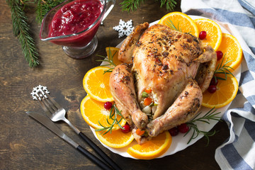 Concept of Christmas or New Year dinner roasted turkey stuffed with rice and Cranberry sauce on wooden table.