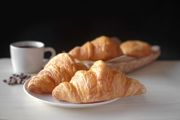 Delicious breakfast with fresh croissants and cup of espresso coffee on wood table.