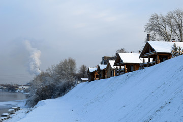 Wooden house. Lots of snow around. Winter season. Cold weather. Smoke from the chimney.