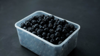 Owoce aronii w przeźroczystym pudełku. Ciemne tło, zbliżenie.