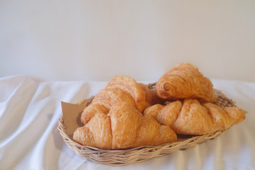 Fresh croissant in basket on white fabric. Tasty buttery croissants.