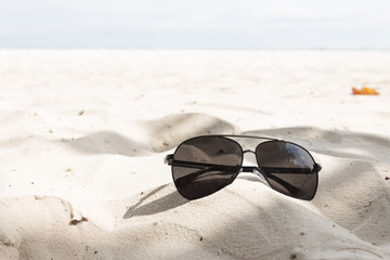 Fototapeta na wymiar Eyewear placed on the sand at the beach.