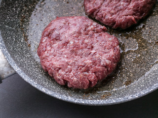 Close-up two raw appetizing juicy burger on a ceramic pan.