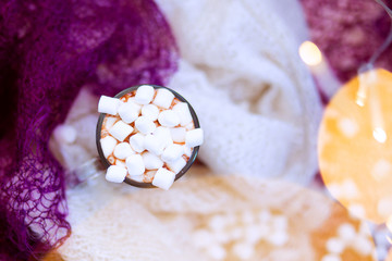 Christmas still life with cocoa with marshmallows wrapped in warm knitted sweaters, top view