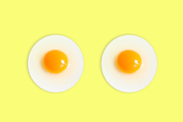 Two Organic round  (White eggs and  yolk )of chicken Cooked high protein good for health decorative isolated on pastel light Yellow  background texture close-up