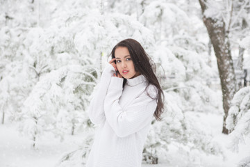 Fototapeta na wymiar Girl in white sweater or pullover in winter snow covered park