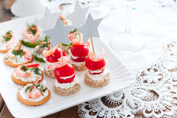 Assorted appetizers canapes with shrimps - with fresh cucumbers, cherry tomatoes, bread, crackers on the festive table, horizontal, copy space