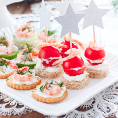 Assorted canapes with shrimps - with fresh cucumbers, cherry tomatoes, bread, crackers at the festive Christmas table, square