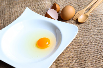 Raw Organic round  (White eggs and  yolk )of chicken decorative food concept   With eggshell and spoon and fork isolated In a white ceramic container background texture close-up