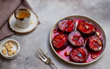 baked plums with honey, cinnamon and hazelnuts. healthy and delicious dessert. light background