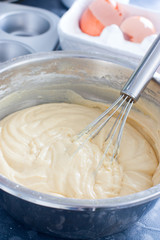 Raw cupcake dough in a metal bowl with a metal whisk, selective focus