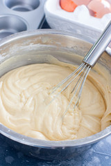 Raw cupcake dough in a metal bowl with a metal whisk, selective focus
