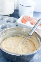 Raw cupcake dough in a metal bowl with a metal whisk, selective focus