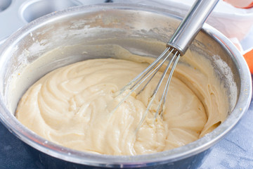 Raw cupcake dough in a metal bowl with a metal whisk, horizontal