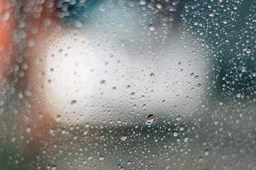 Blurred rainy window with red bokeh light