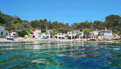 Spain, Catalonia, Mediterranean coast with peaceful fishermen houses on a rocky beach seen from sea...