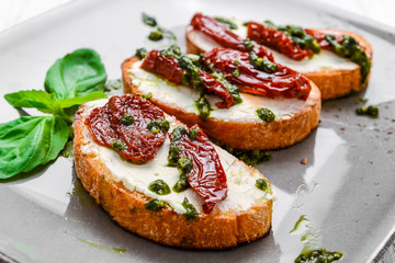 Tasty savory Italian appetizers, or bruschetta, on slices of toasted baguette garnished with basil
