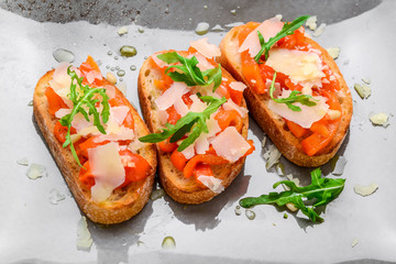 Tasty savory Italian appetizers, or bruschetta, on slices of toasted baguette garnished with basil