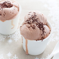Homemade chocolate ice cream in white cups on a winter tablecloth, New Year's dessert, square