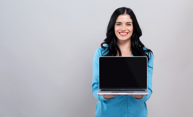 Young woman with a laptop computer on a gray background - Powered by Adobe
