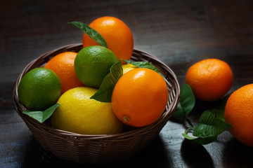 Juicy ripe slices of orange, lemon, grapefruit and lime on a dark background. Sliced citrus in a basket on a brown wooden table. Fruit mix, top view close-up.