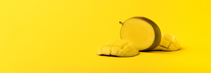 mango fruit with mango sliced cubes on yellow background, panoramic image with space for text.