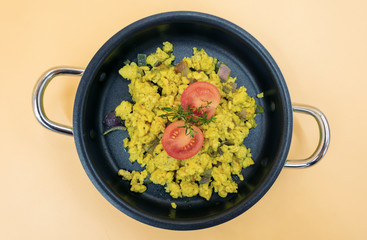 frisch gebratenes Rührei in der Pfanne mit Tomaten und Kräutern