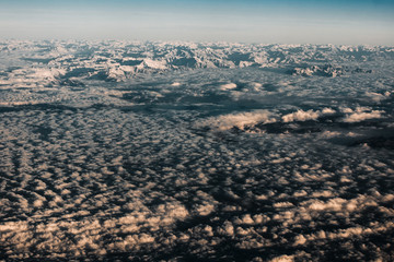 Aerial view from the plane on the panorama of the Alp mountains and hills ridge. Mountain peak of rocks covered by clouds and fog. View from above on mountain landscape.