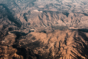 Aerial view from the plane on the panorama of the Alp mountains and hills ridge. Mountain peak of rocks covered by clouds and fog. View from above on mountain landscape.