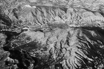Aerial view from the plane on the panorama of the Alp mountains and hills ridge. Mountain peak of rocks covered by clouds and fog. View from above on mountain landscape.